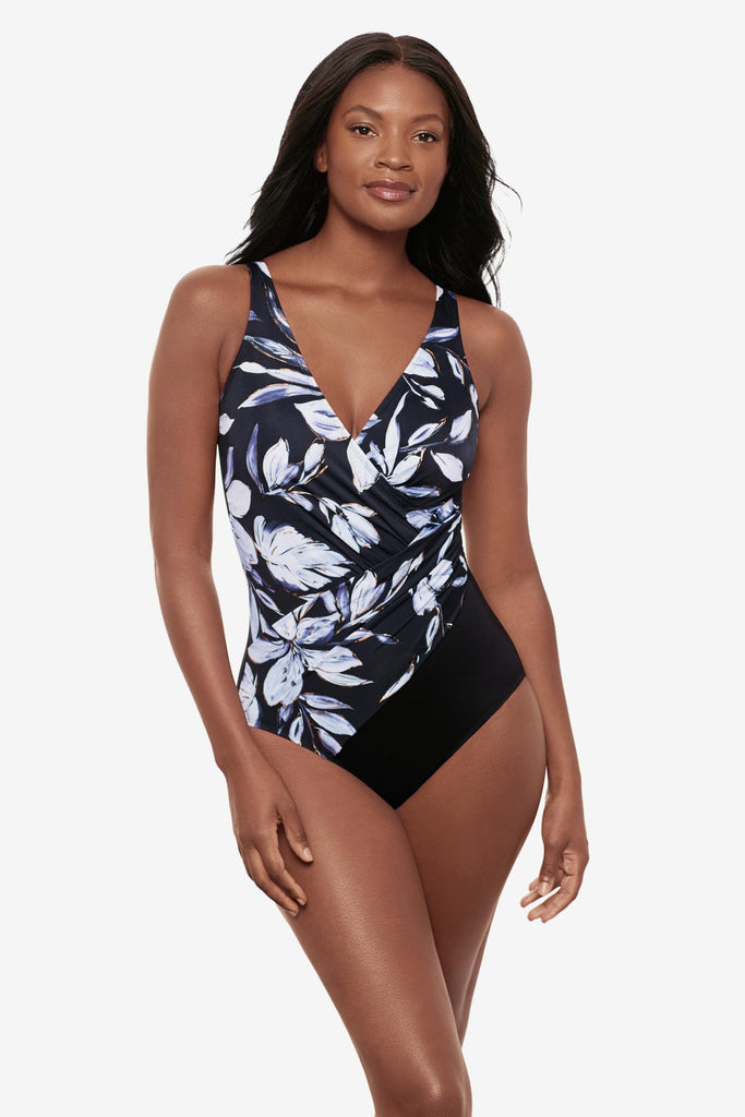 Woman wearing a black and white floral printed one-piece swimsuit with a V neckline