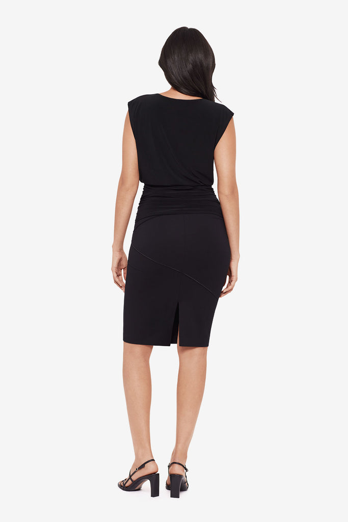 Woman turned away wearing a drapey black blouse with matching black skirt
