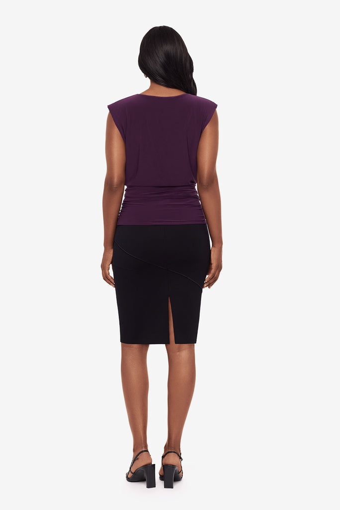 Woman turned away wearing a plum-colored blouse with a black skirt