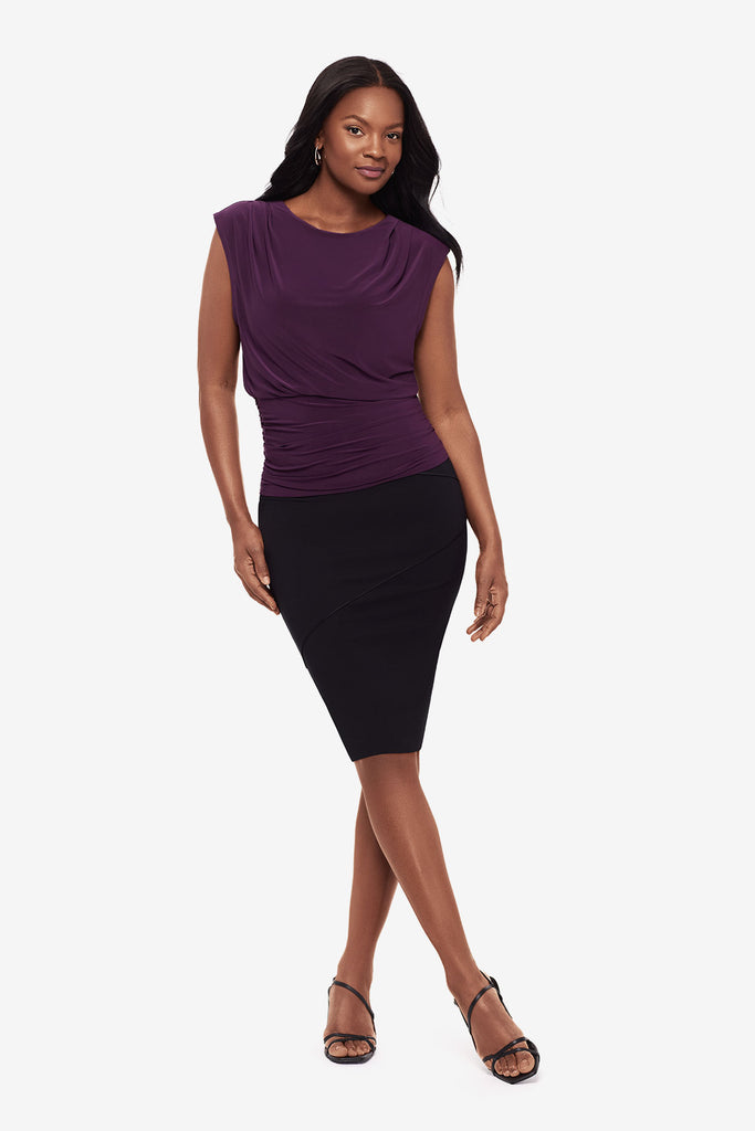 Woman wearing a plum-colored blouse with a black skirt