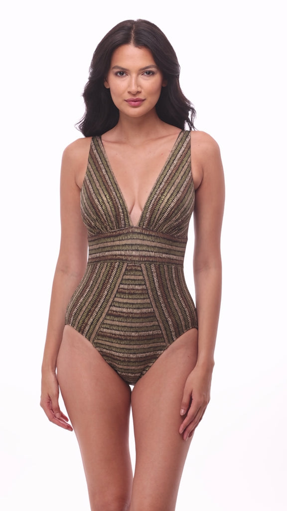 Woman wearing a shimmery golden brown striped one-piece swimsuit with a deep V neck